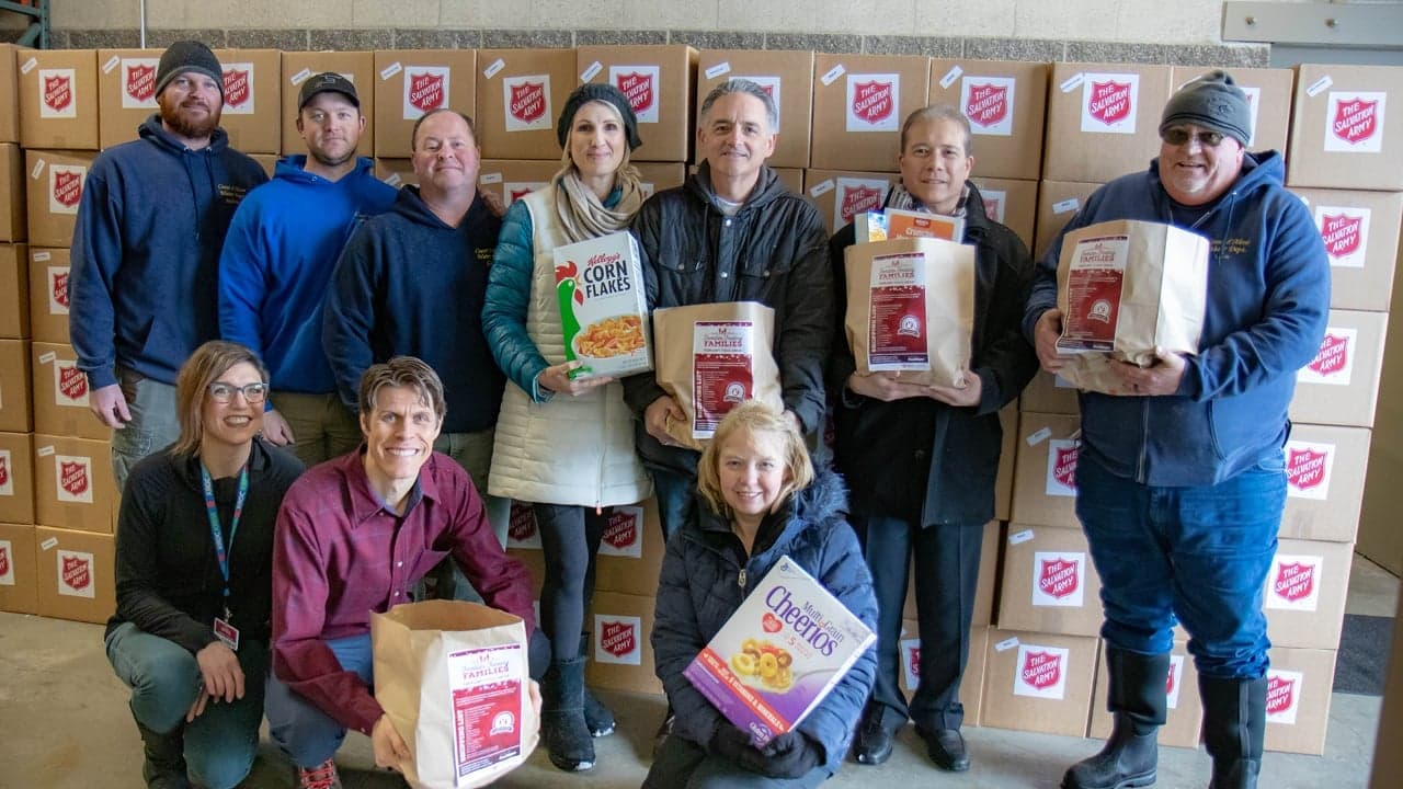 Donors standing with food donations in hand and boxes behind them.